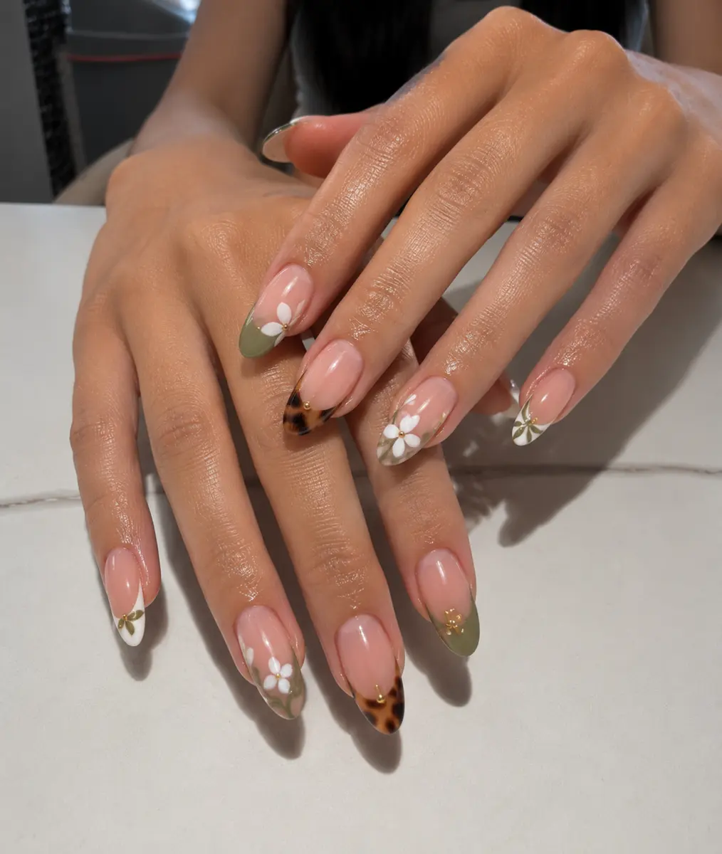 Nude nails with daisy floral accents and a tortoiseshell tip